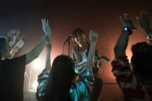 Musician performing live on stage with enthusiastic audience at nightclub.