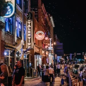 Bustling city street with colorful neon signs and people enjoying nightlife.