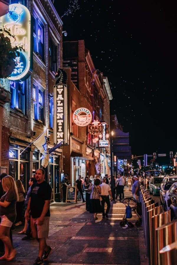 Bustling city street with colorful neon signs and people enjoying nightlife.