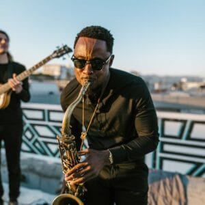 Talented musician performing on saxophone outdoors during sunset, capturing vibrant musical energy.